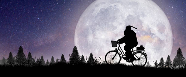 Père Noël à vélo sous le ciel étoilé et la pleine lune